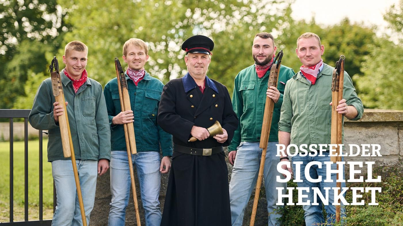 Mann läuft auf dem Bleichesteg, im Vordergrund des Bildes sind blühende Blumen zu sehen 