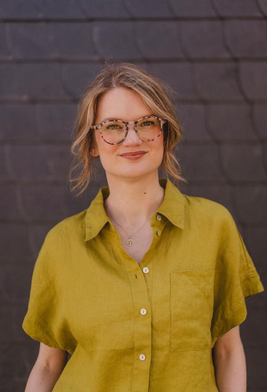 Portraitbild von einer Frau mit einer grünen Bluse und Brille